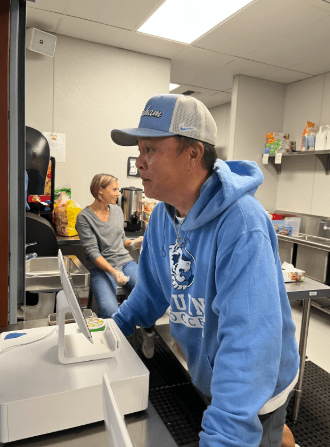 Girls soccer varsity head coach Erich Rabago works the snack shack during a football game to raise funds for the soccer team
