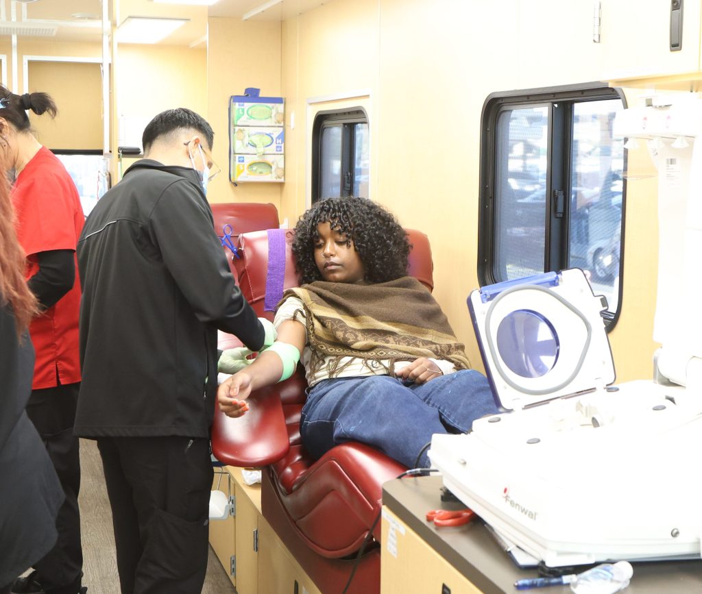 BeEmnet Amare (11) donates blood in the Stanford Blood Center van.