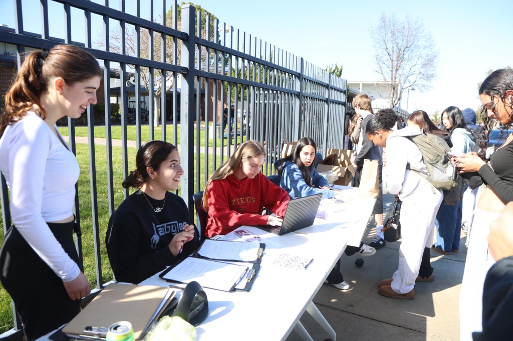 Service commission head Sevin Sabei (11) volunteers with ASB President Lilly Murphy (12) in front of the van.